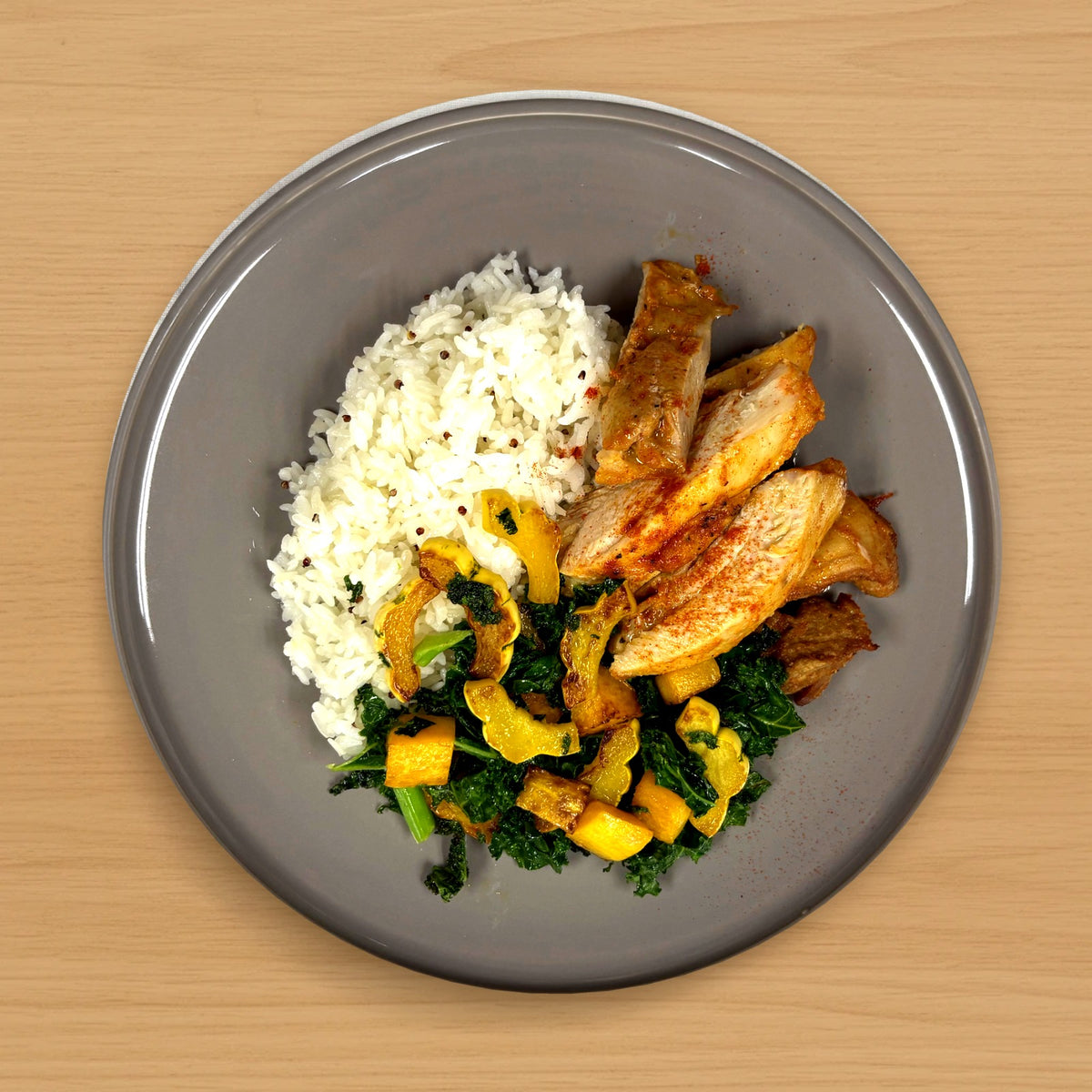 Pimentón chicken thigh with butternut squash, kale and quinoa rice on a wood table